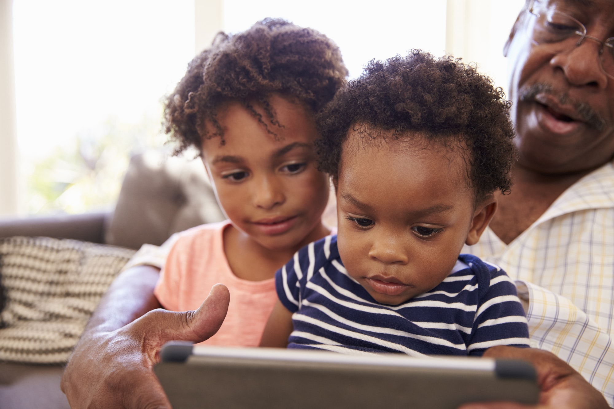 Grandfather And Grandchildren At Home Using Digital Tablet