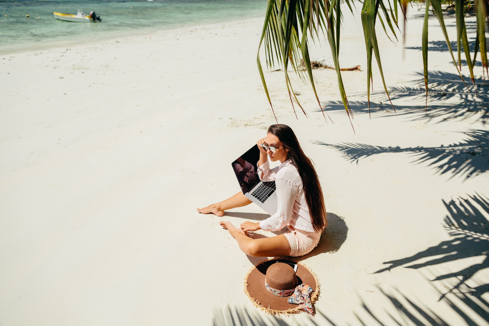 Remote working woman on beach in tropics