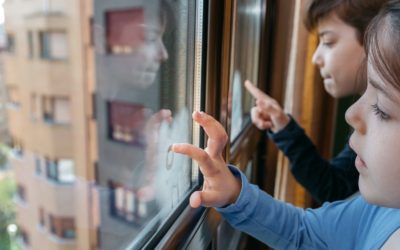 Two children in coronavirus lockdown drawing on the window