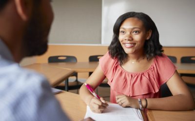 High School Tutor Giving Female Student One To One Tuition At Desk