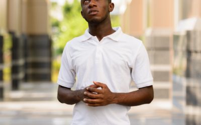 Portrait of stressed young African man praying and looking up outdoors