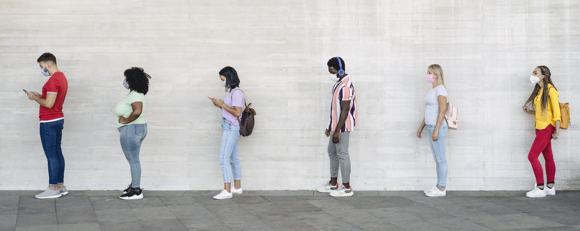 Young people from different cultures and race waiting in queue outside shop market
