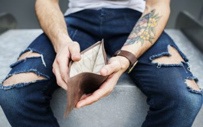 Arm with tattoo holding empty wallet