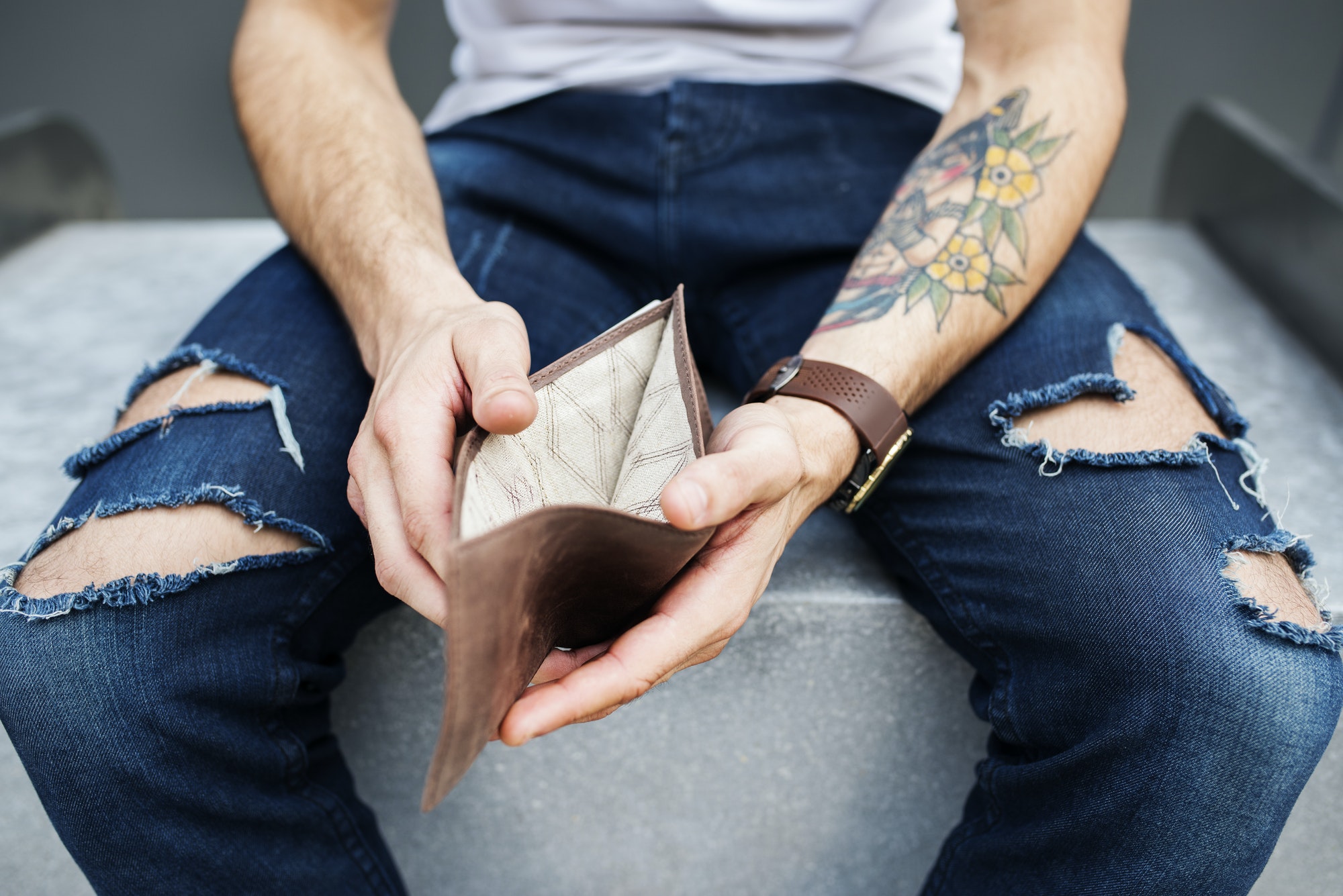 Arm with tattoo holding empty wallet