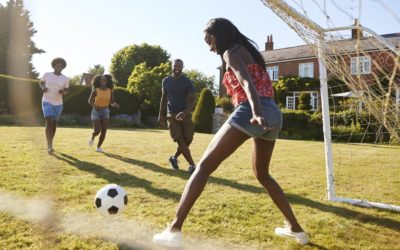 Black woman saving goal during a game of football in garden