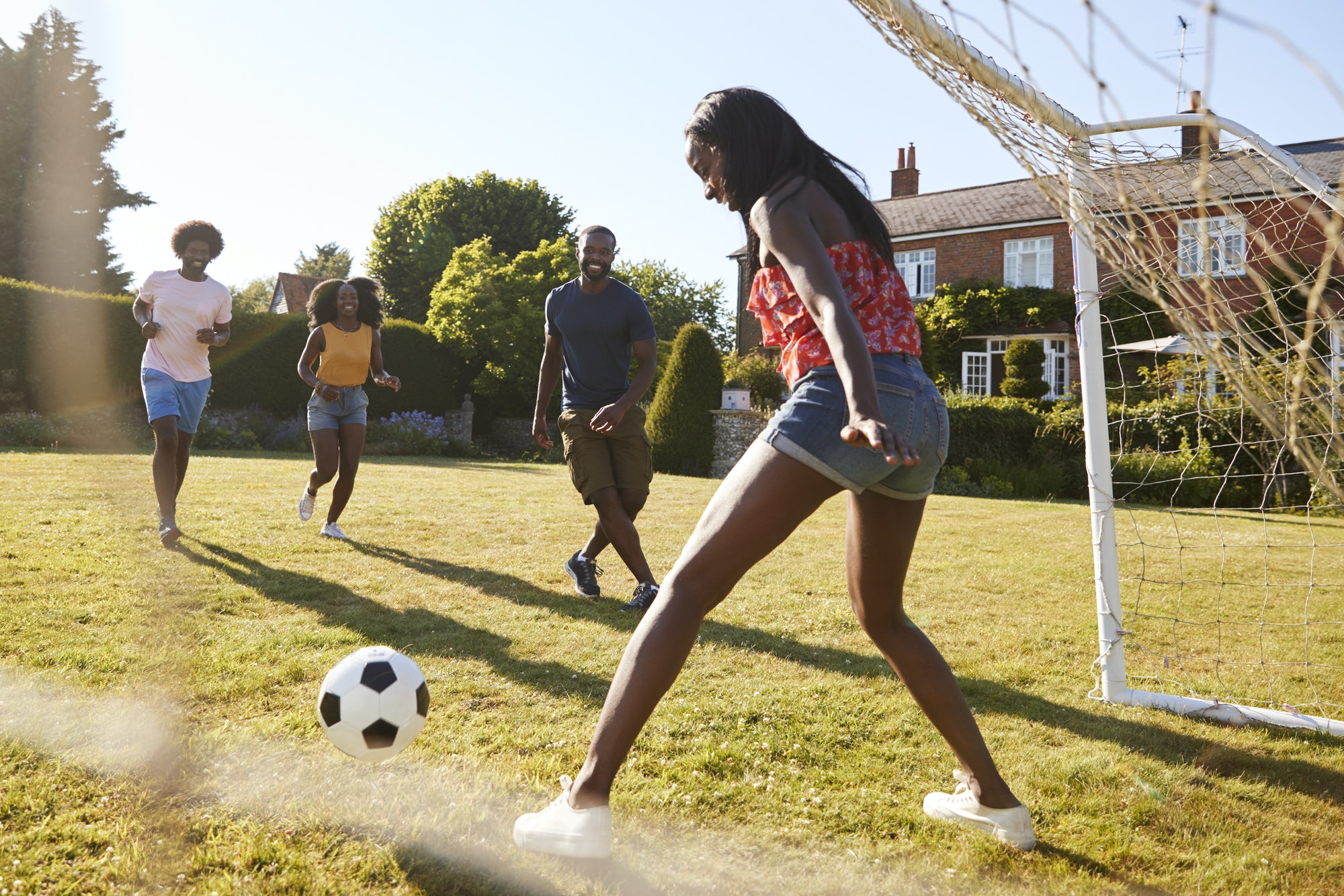 Black woman saving goal during a game of football in garden