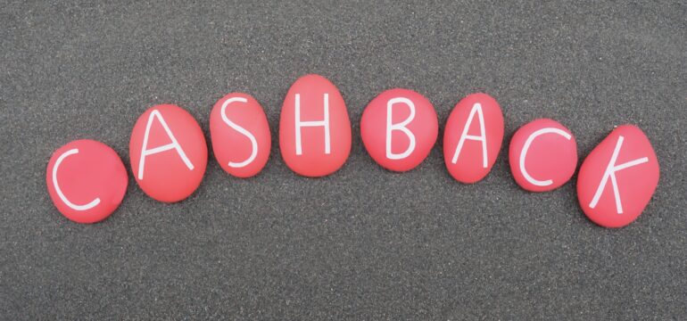 Cashback, reward program word composed with red colored stone letters over black sand