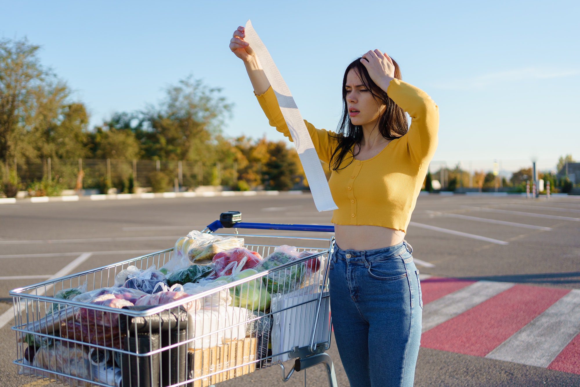 Woman checks paper check after shopping increase in food prices, spending money in hypermarket.