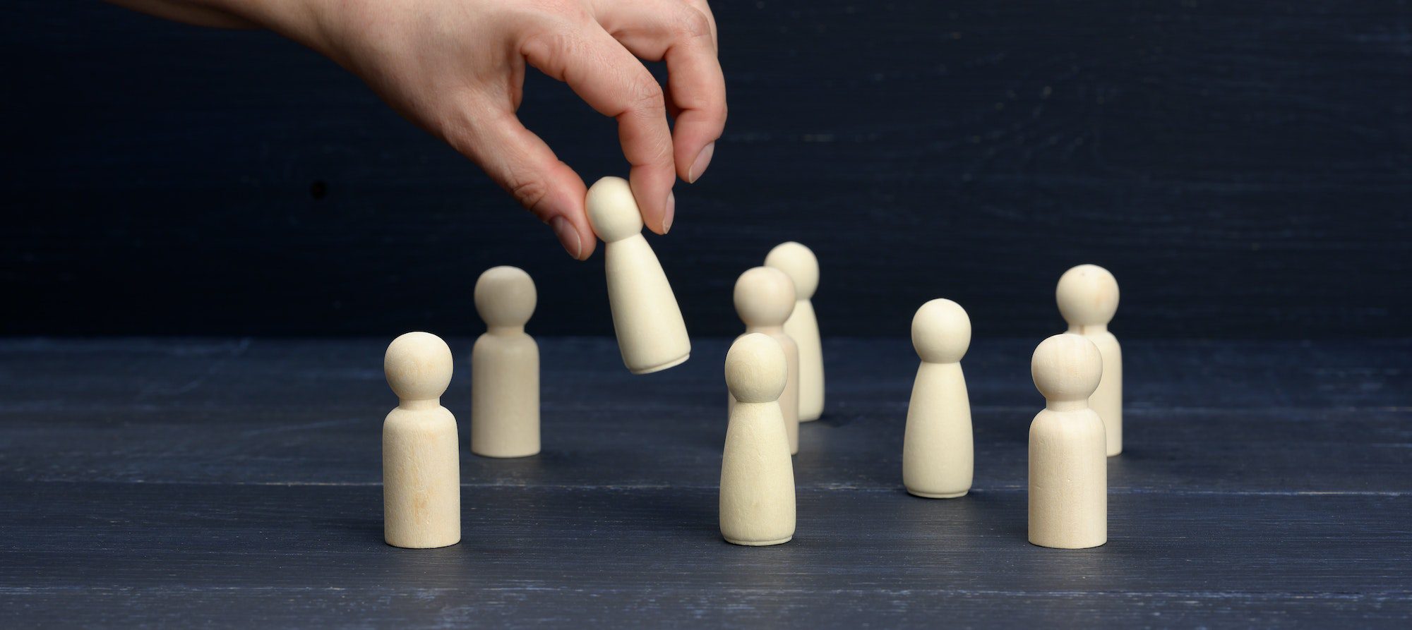 Female hand holds a wooden figurine above the crowd.
