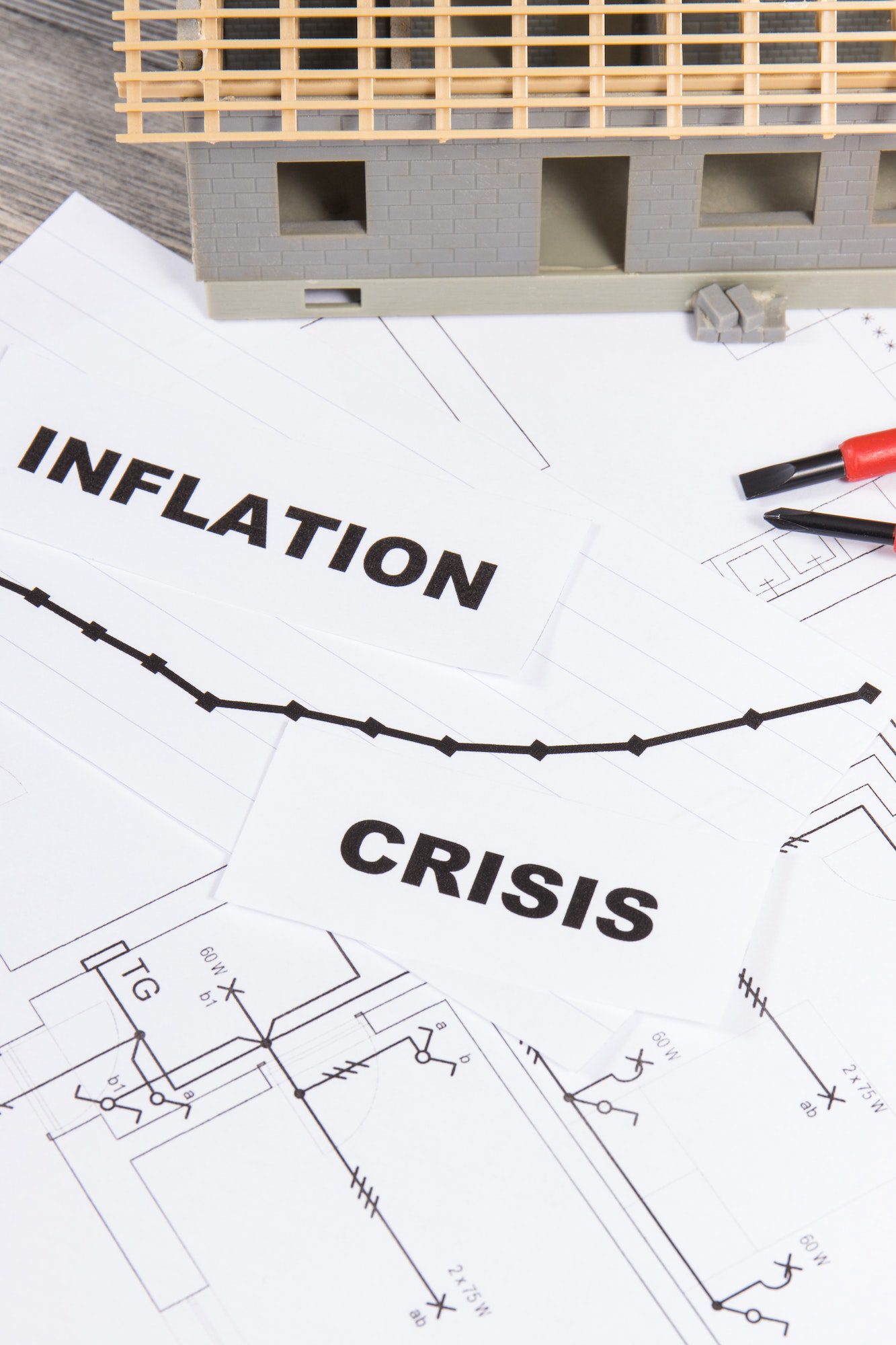 Inscriptions crisis and inflation, small house under construction on electrical diagrams Inscriptions crisis and inflation, small house under construction on electrical diagrams