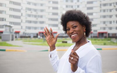 black girl with keys to apartment on background of multi-storey building. home buying and moving
