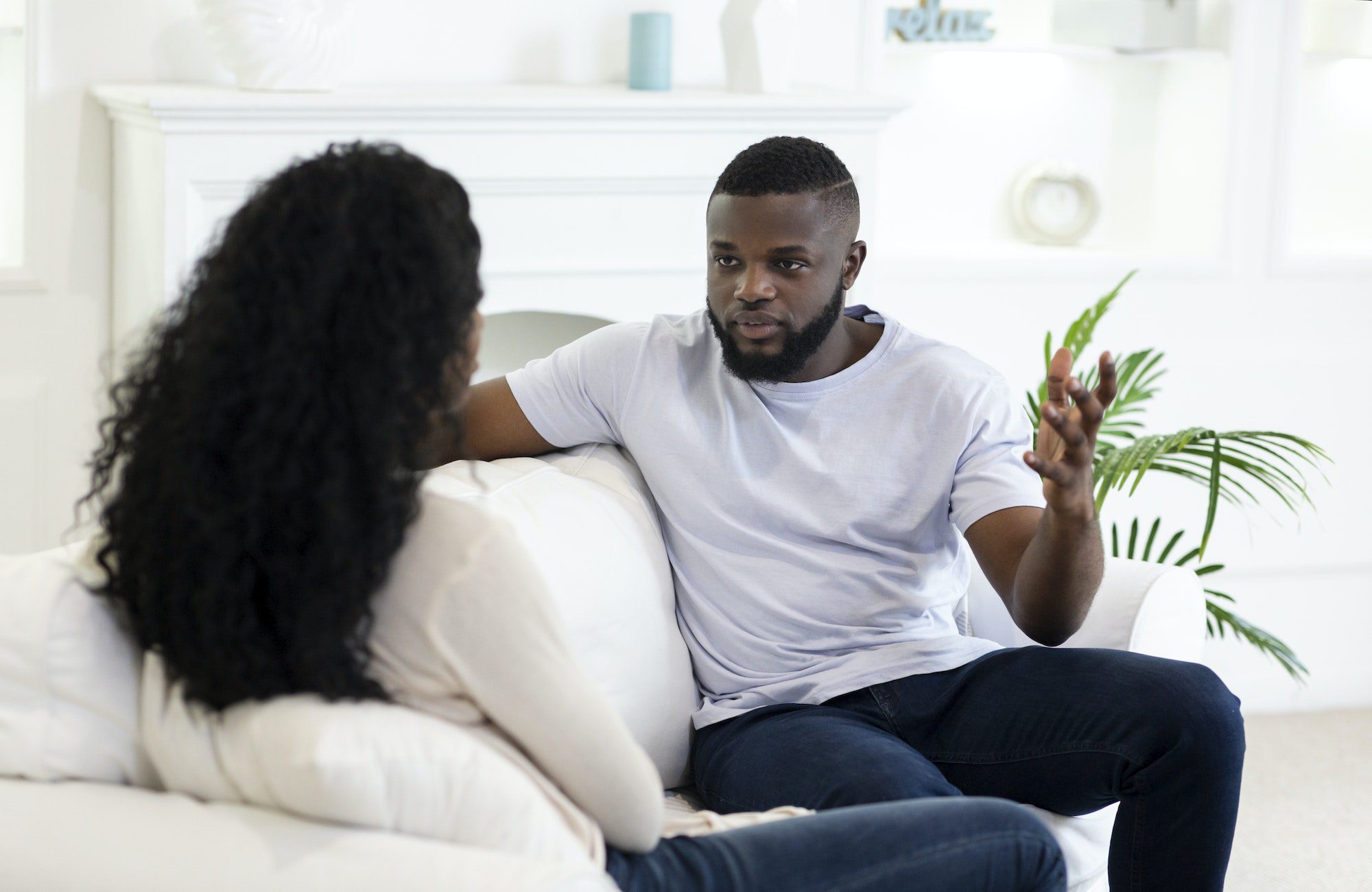 Angry man blaming his girlfriend sitting at sofa at home