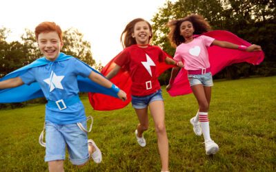 Carefree diverse superhero children running along meadow