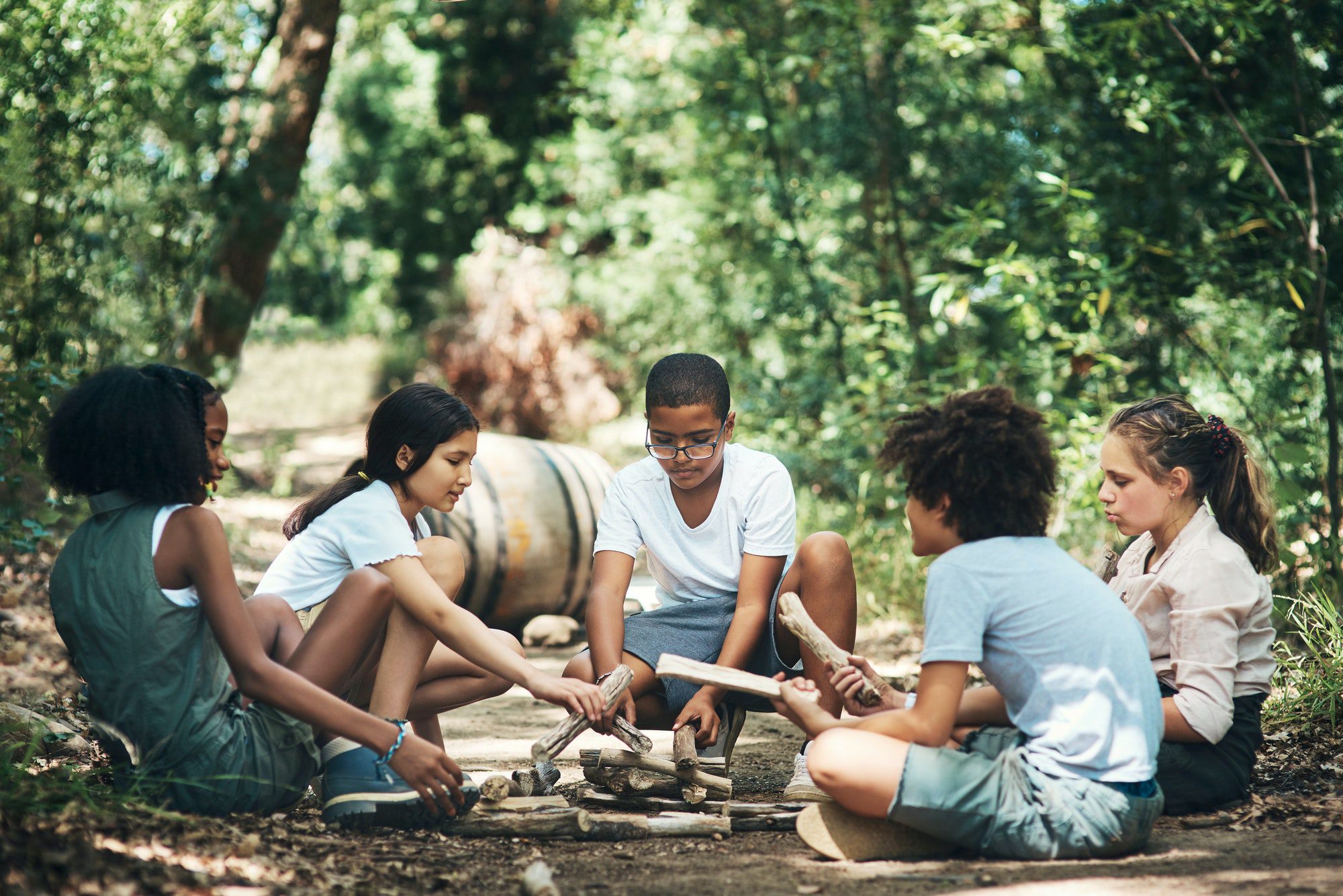 Going back to the basics. Shot of a group of teenagers building a pile of wood at summer camp.