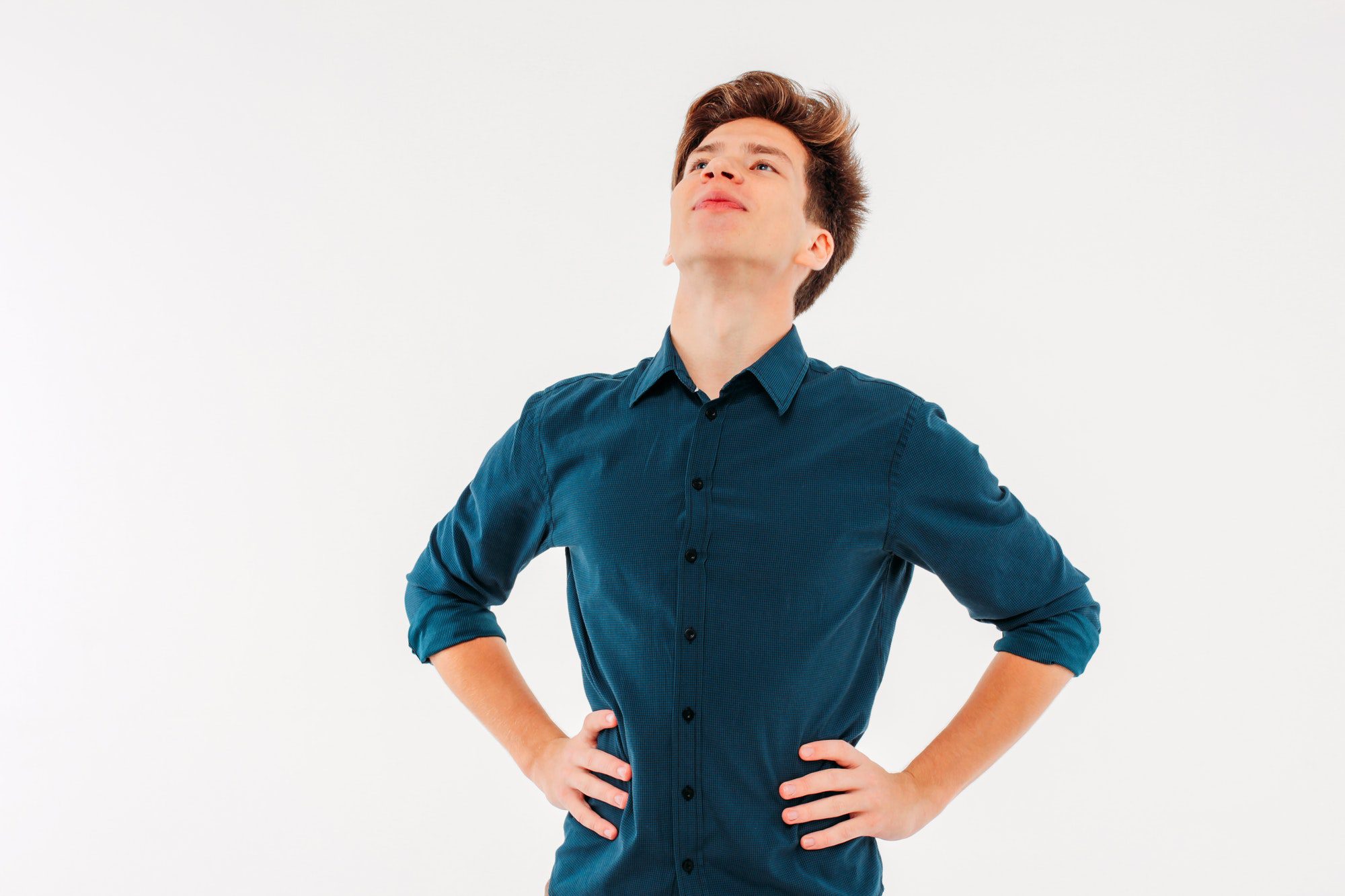 The young man stands with his head up on a white background