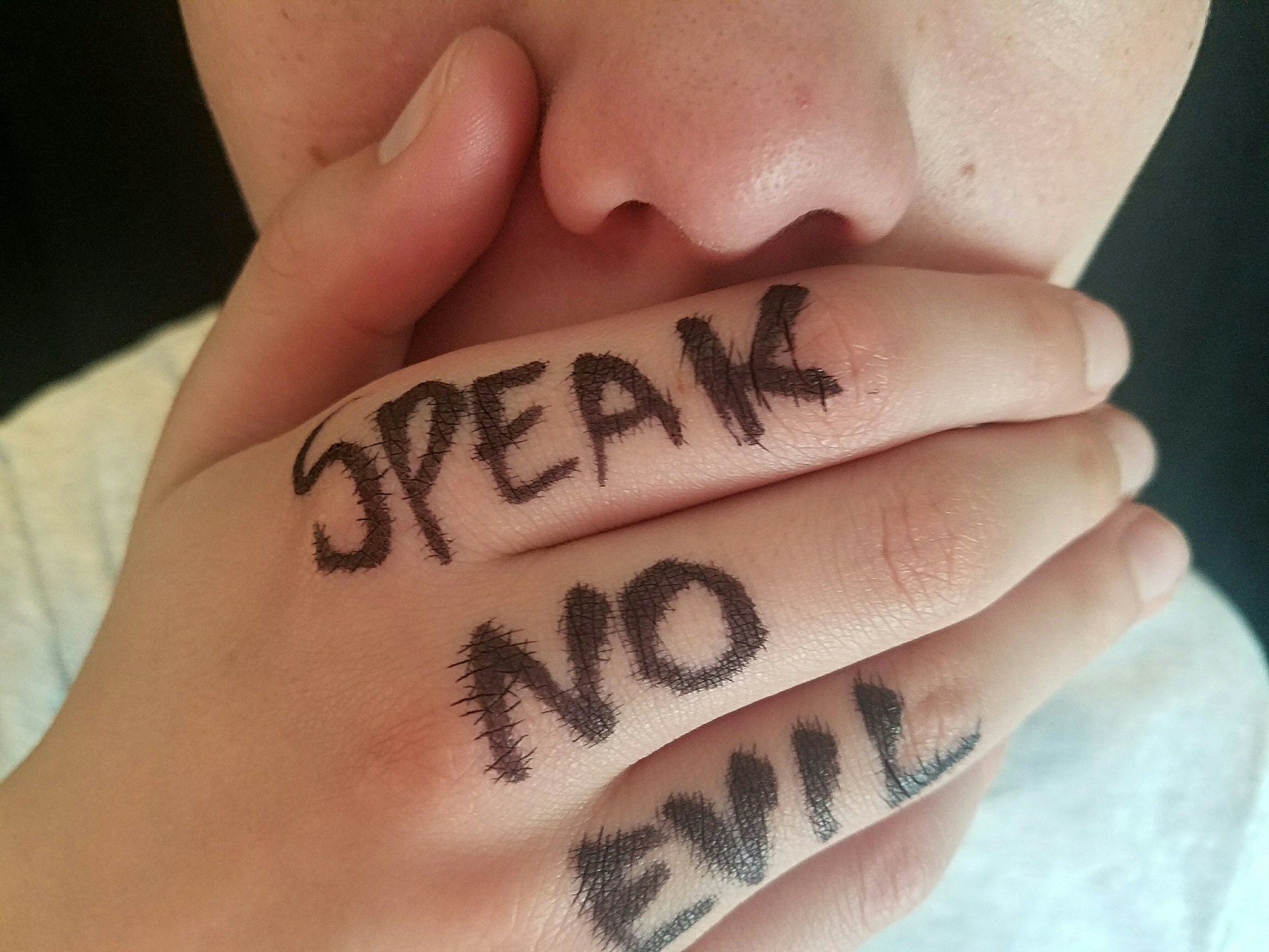 Conceptual image of hand with Speak No Evil written on fingers covers mouth.