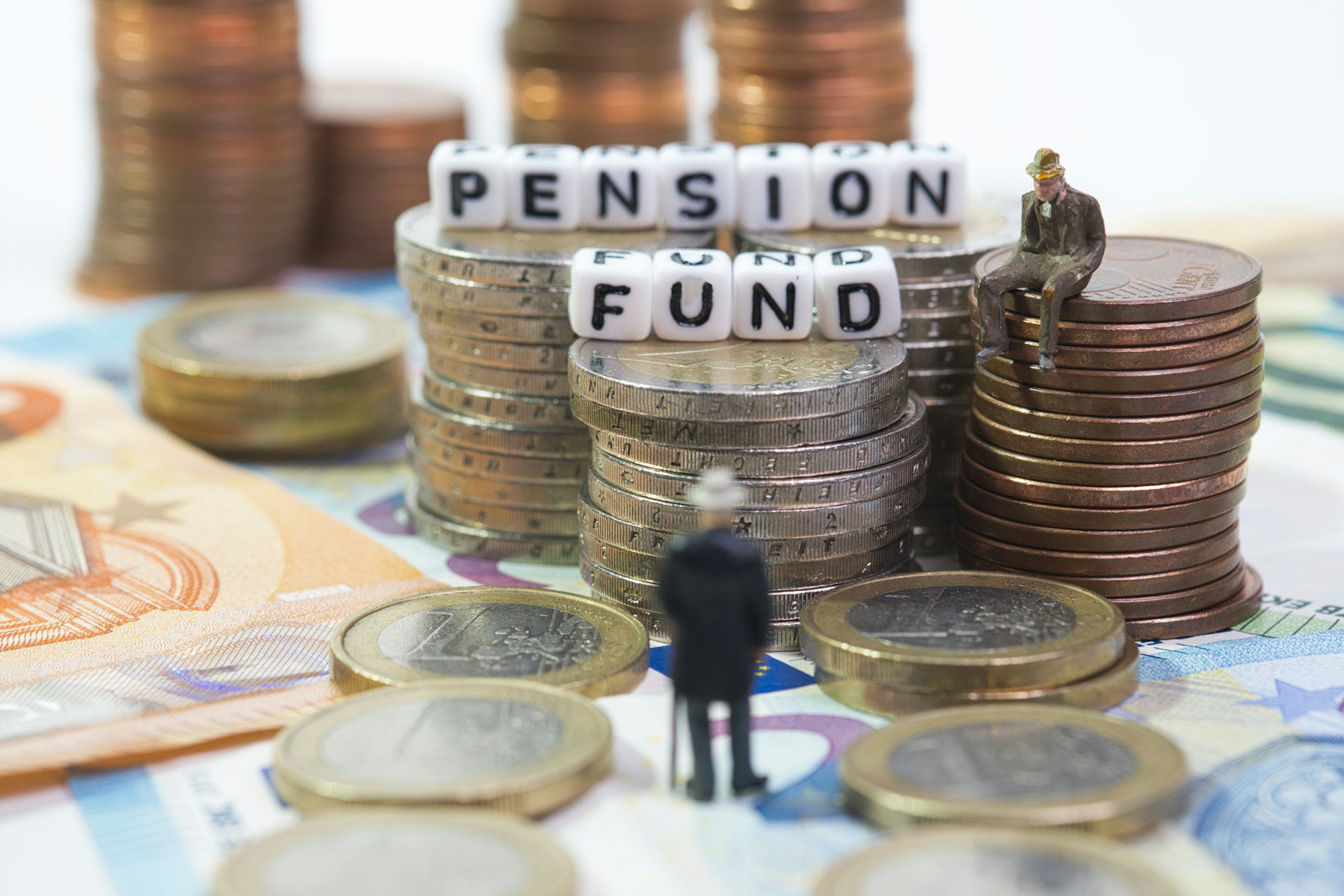 A pensioner stands in front of coin towers with the inscription pension fund