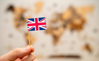 British flag in mans hand on the world map background.