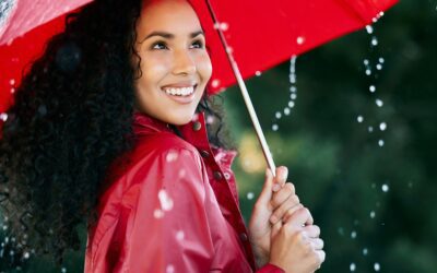 Its raining, its pouring. Shot of a beautiful young woman standing in the rain with an umbrella.