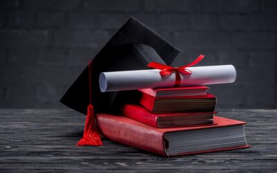 Stack of books with diploma and graduation hat on table