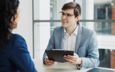 Man in suit interviews woman holding clipboard.