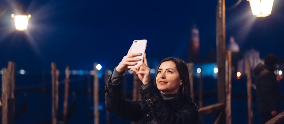 Beautiful young woman taking selfie in the city