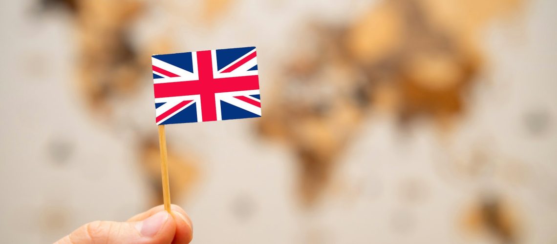 British flag in mans hand on the world map background.