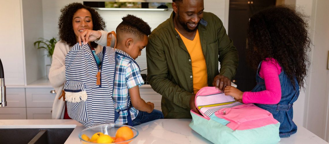 Happy african american parents and children preparing backpacks for school