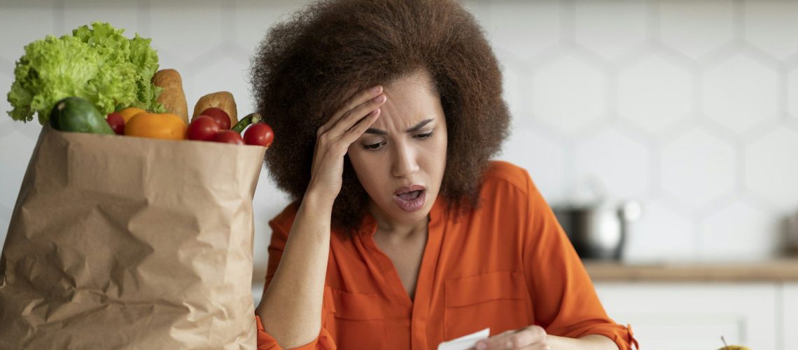 Inflation Concept. Shocked Black Woman Checking Bill After Grocery Shopping