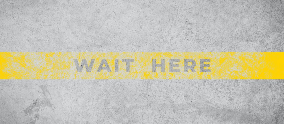 Wait Here sign on aged concrete floor